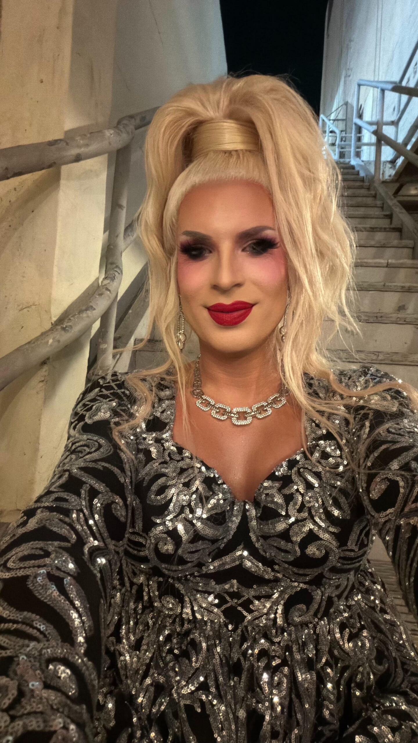 Katya Zamolodchikova taking a selfie in a ponytail and silver and black dress