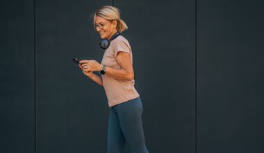 Woman walking wearing fitness tracker, smiling and looking at phone to check step count