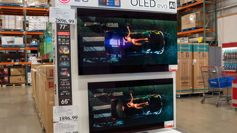 A store display featuring LG OLED evo AI TVs. One is a 77-inch screen priced at $2,896.99.