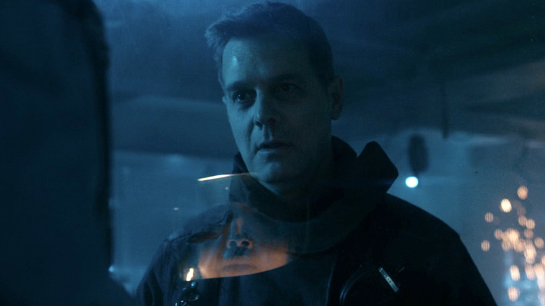 Bobby Nash behind a glass wall in a dark lab, speaking