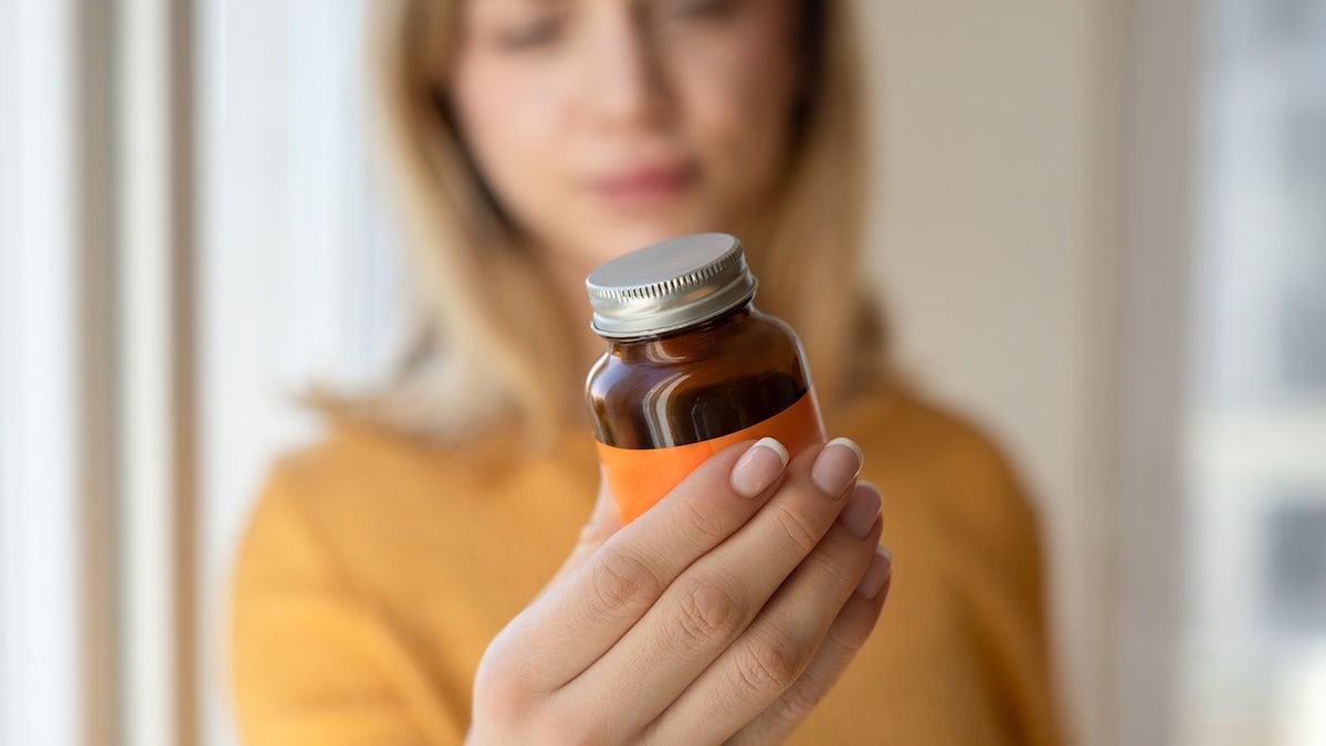 Woman holding a supplement bottle with both hands