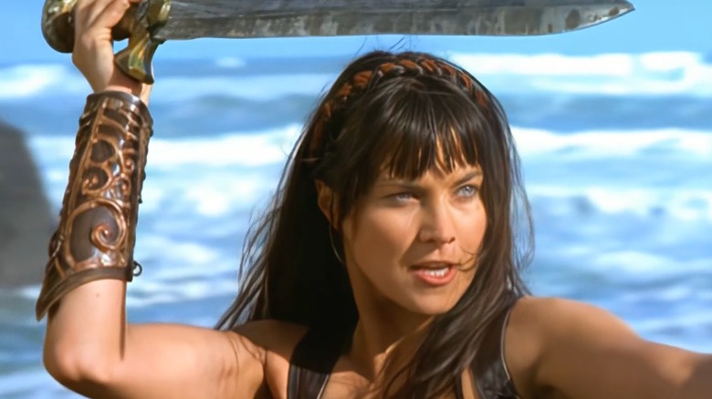 Xena holding a sword over her head outside