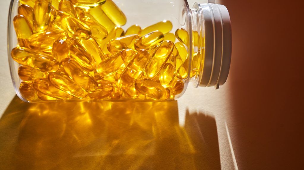 A clear bottle of vitamin D capsules tipped on its side