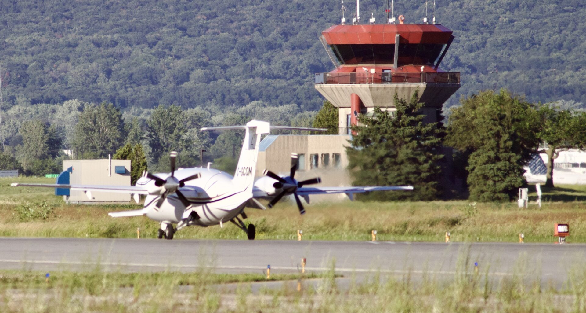 A small aircraft taxis down the runway past the control tower.