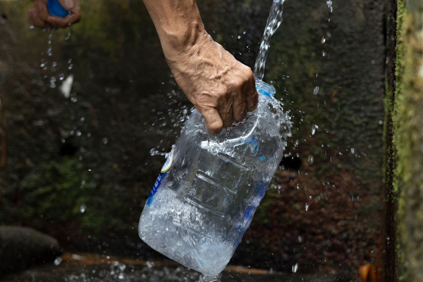 A person fills a container from a natural spring in Trujillo Alto on August 6.