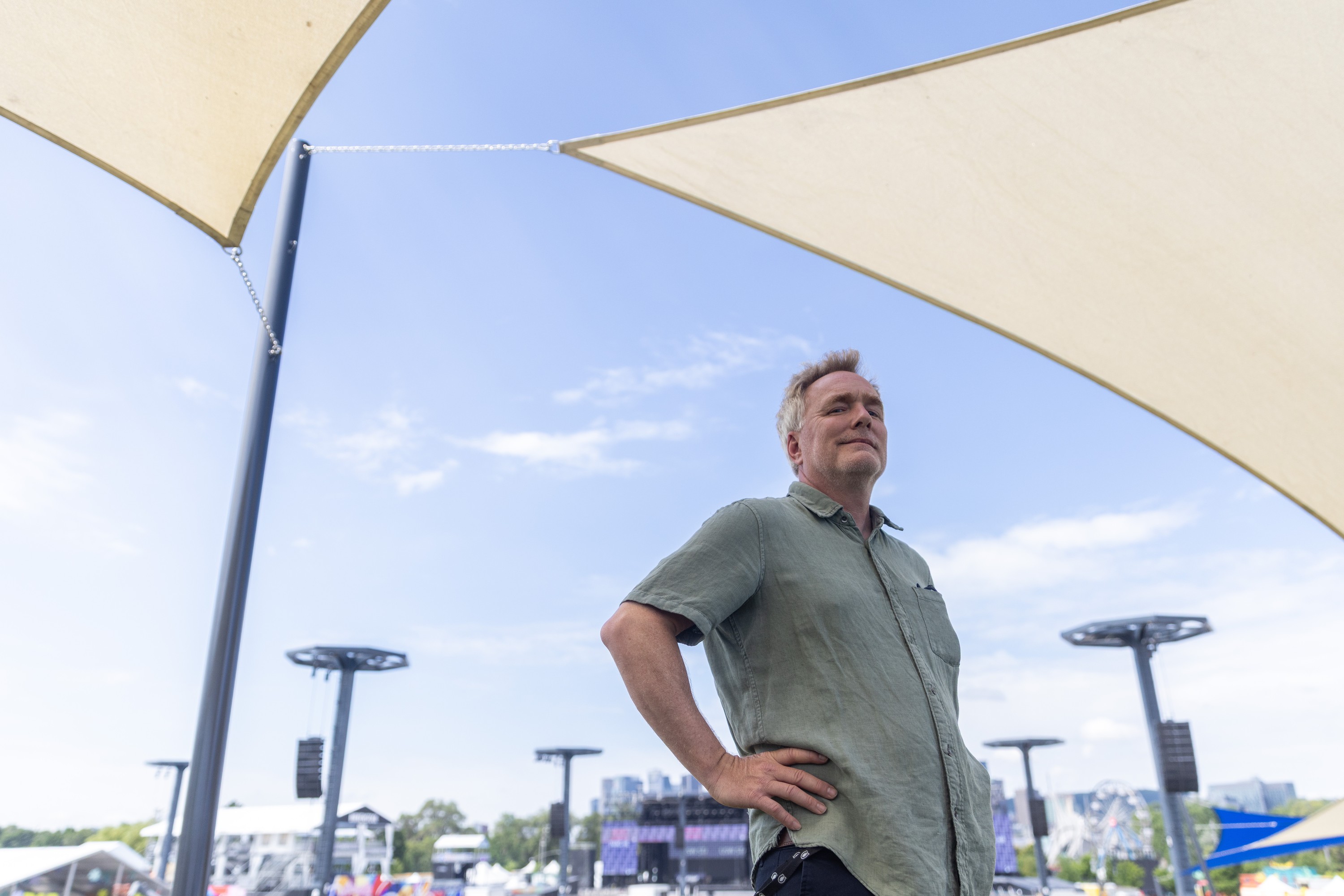 Man stands in front on tents on festival site.