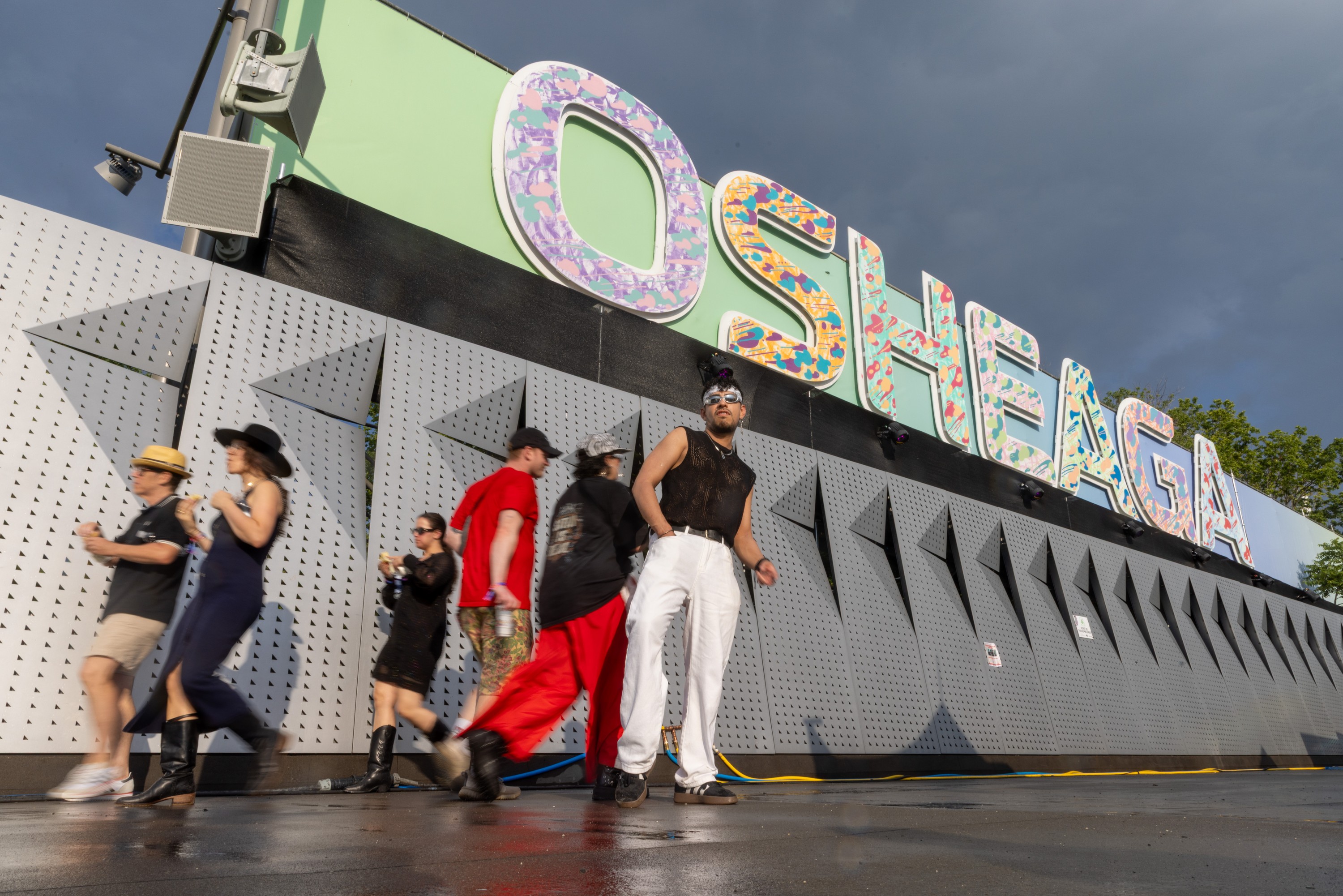 Eugene Ruiz strikes a pose underneath the Osheaga sign at the Osheaga Music and Arts Festival
