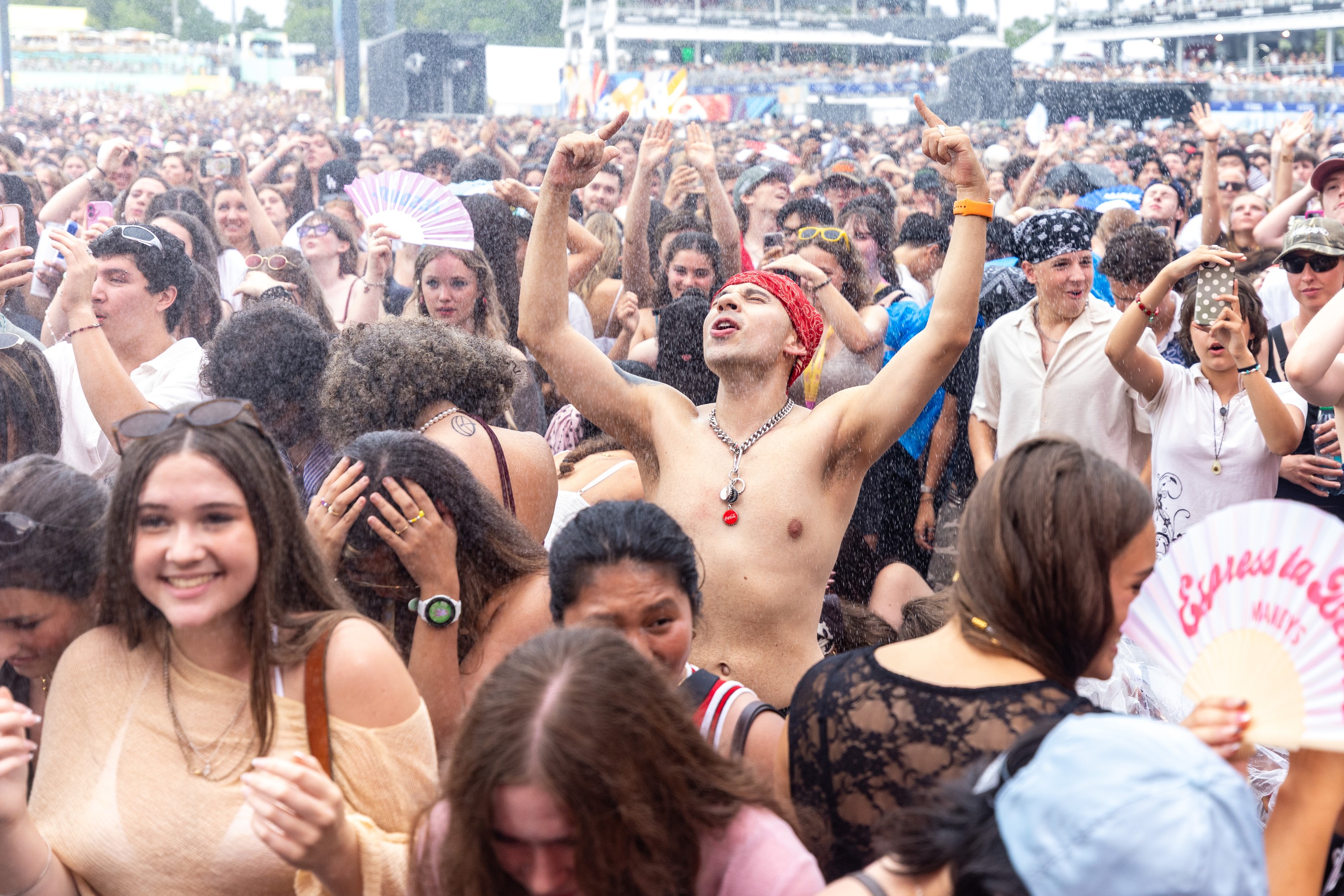Festivalgoers dance under a spray of mist at the Osheaga Music and Arts Festival