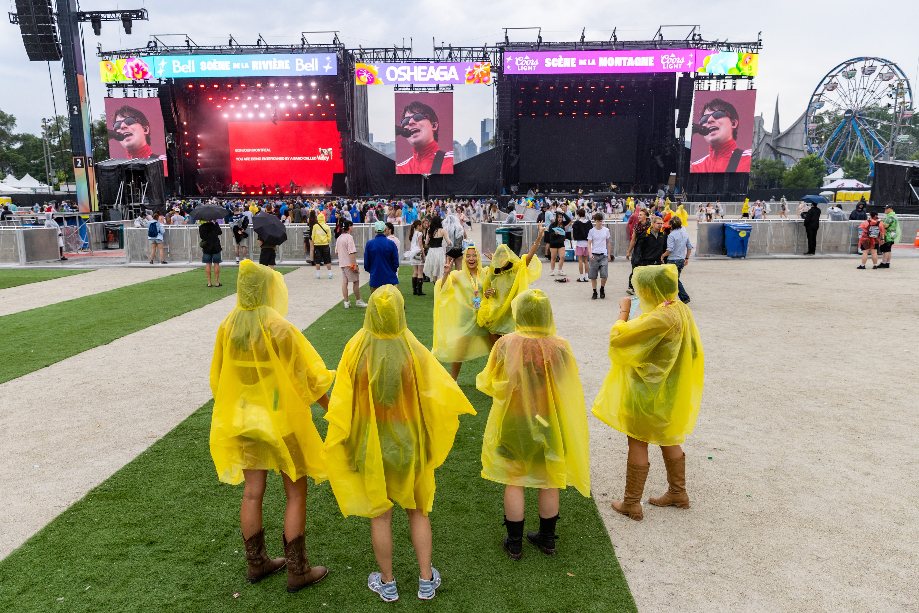 Two women strike a pose as friends take a picture during a rain shower at the Osheaga Music and Arts Festival