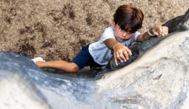 Seen from above, a boy looks determined as he climbs a rock wall.