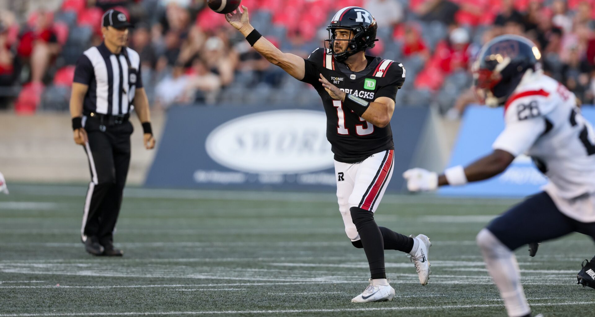 A game official keeps a close eye on the action as Redbalcks QB Jake Maier eludes pressure from the Alouettes' Tyrice Beverette and throws the ball.
