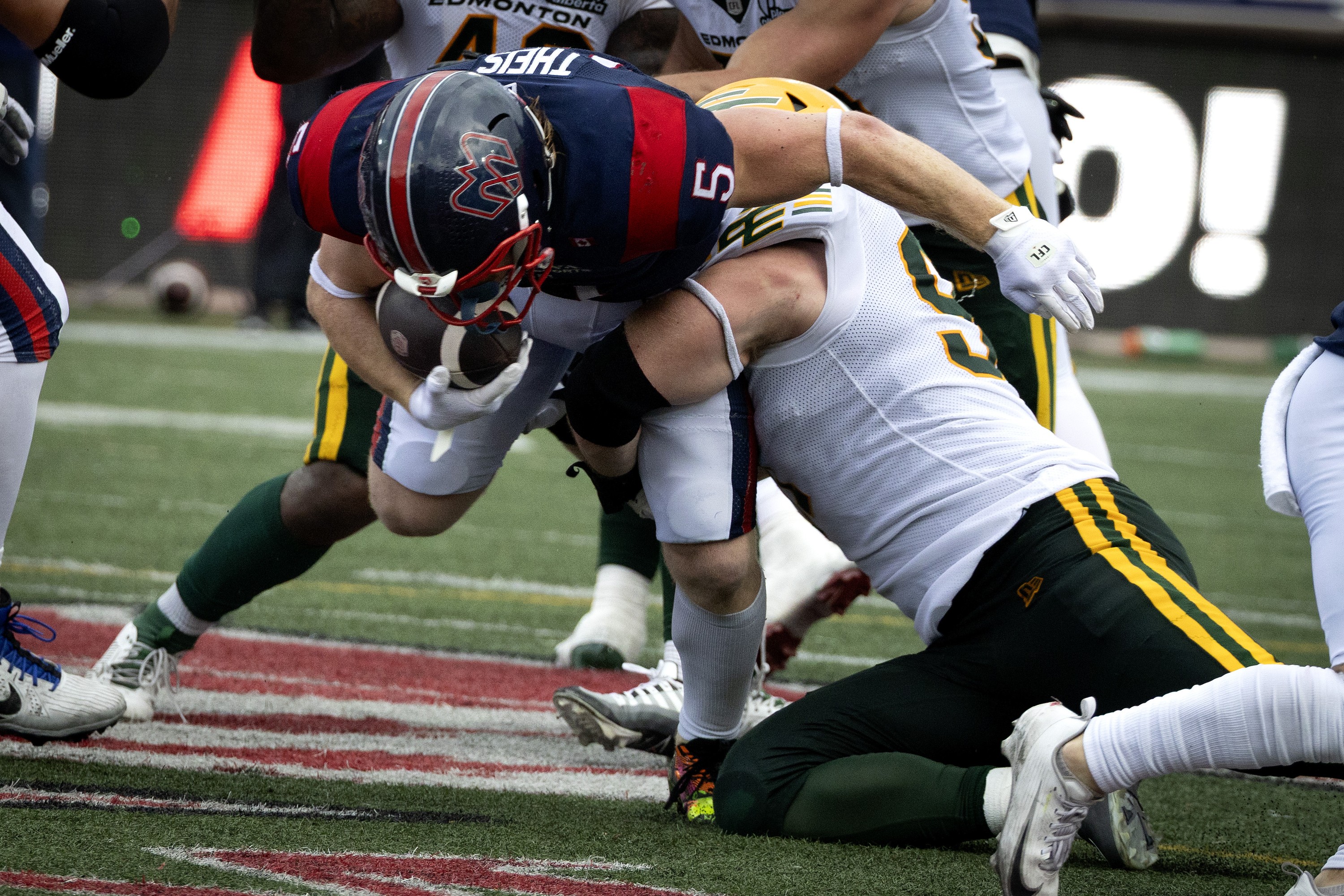 Alouettes running-back Travis Theis is tackled by Elks defensive-lineman Gavin Meyer.