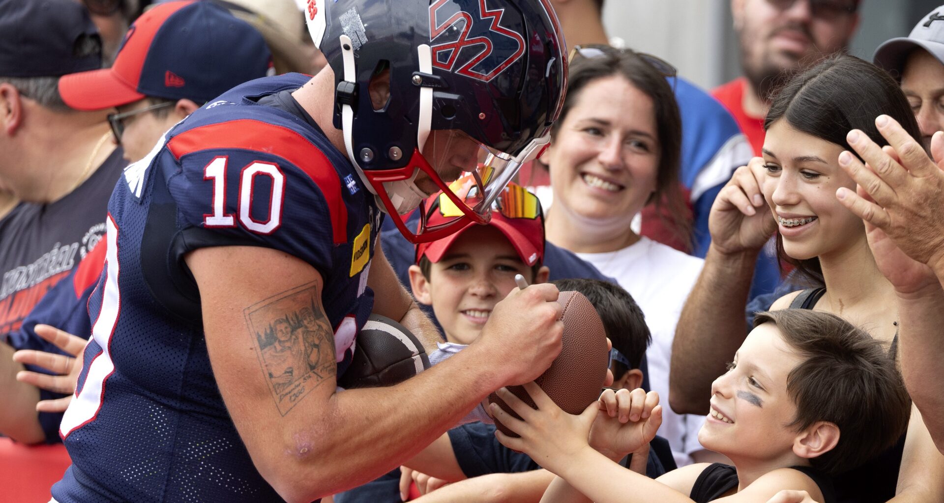 Alouettes quarterback Davis Alexander signs a ball for a young fan.