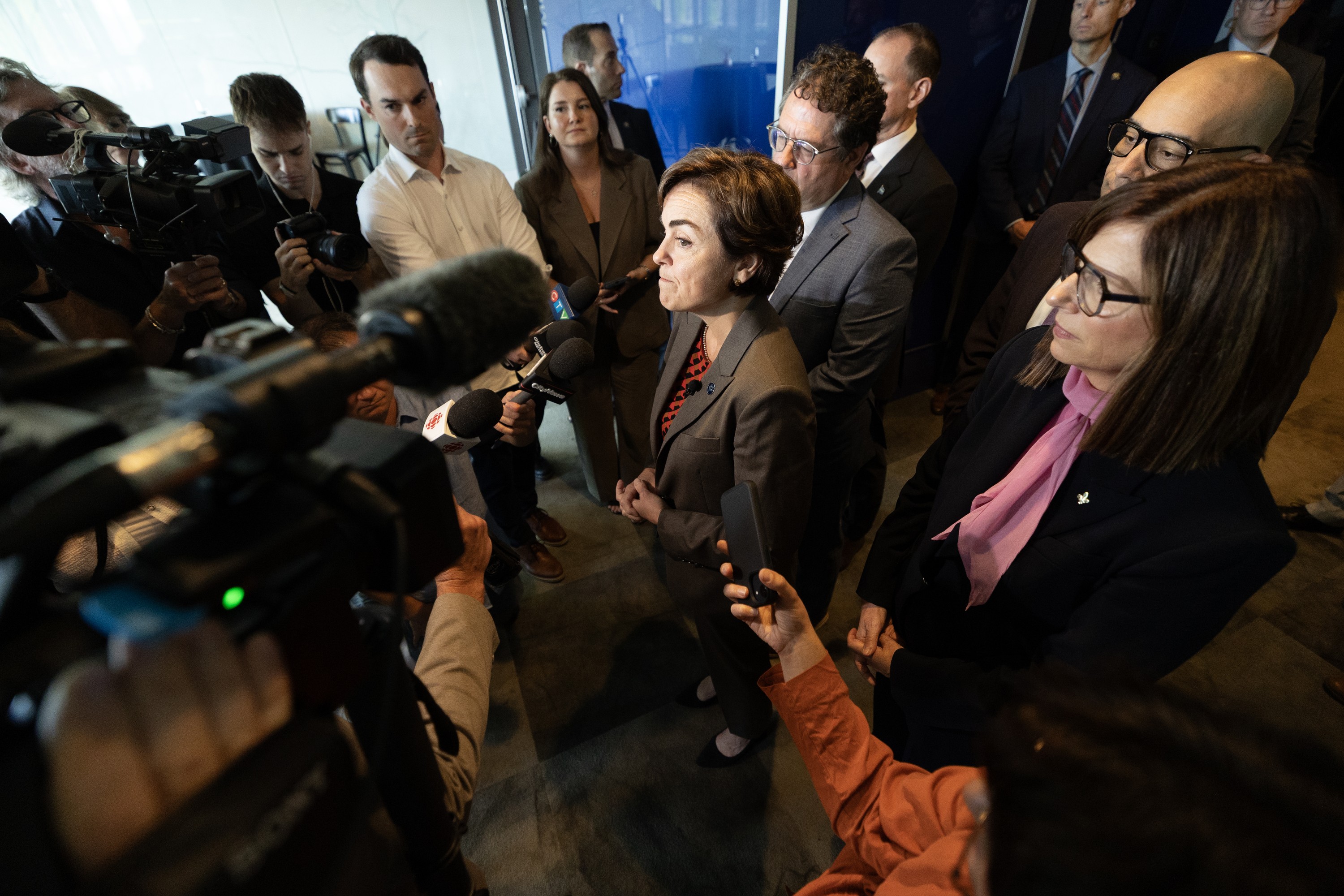 Christine Fréchette surrounded by media, microphones and cameras.