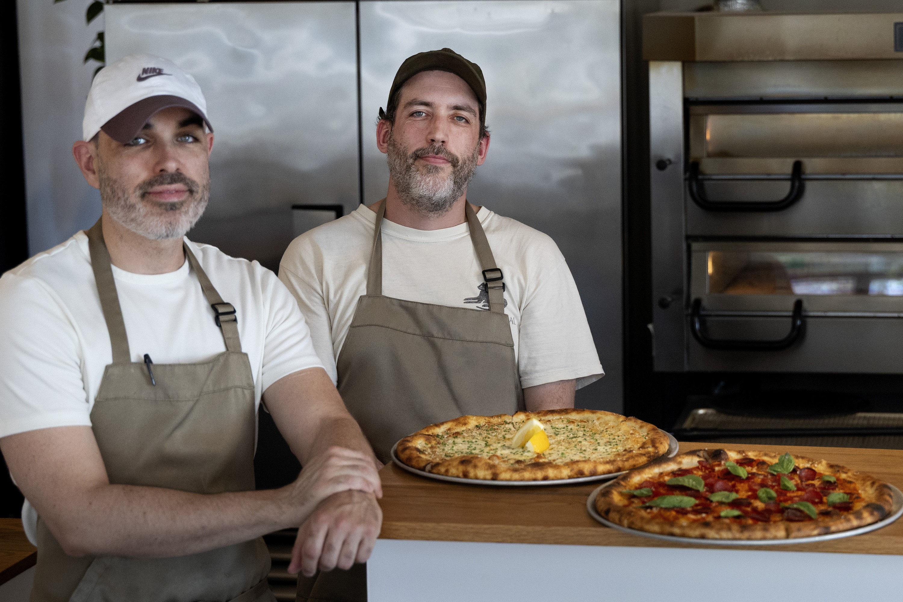 David Reilly, left, and Percy Carrière pose at Maps with two pizzas.