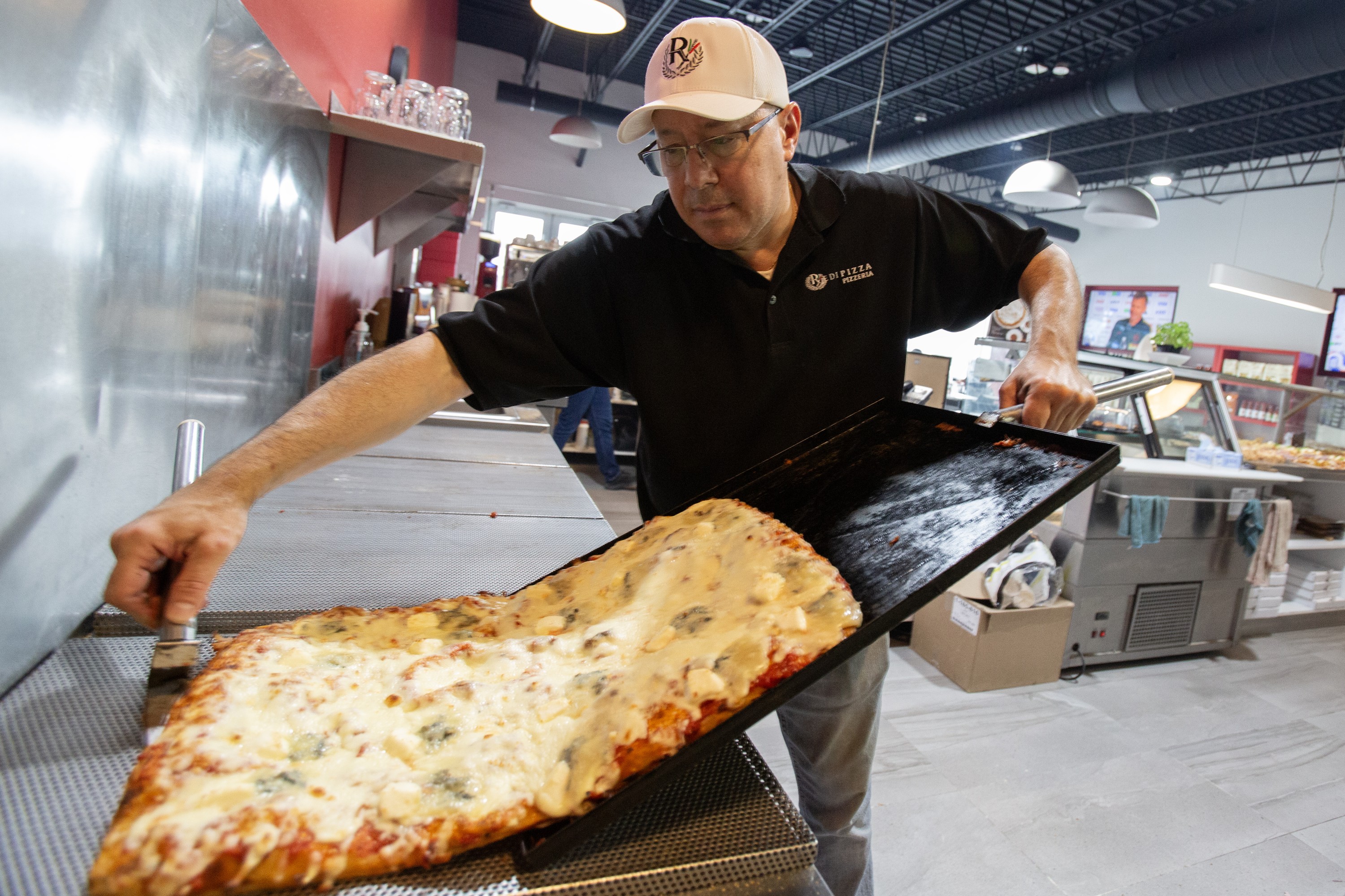 Michele Casala at Redipizza slides out a large rectangular pizza.