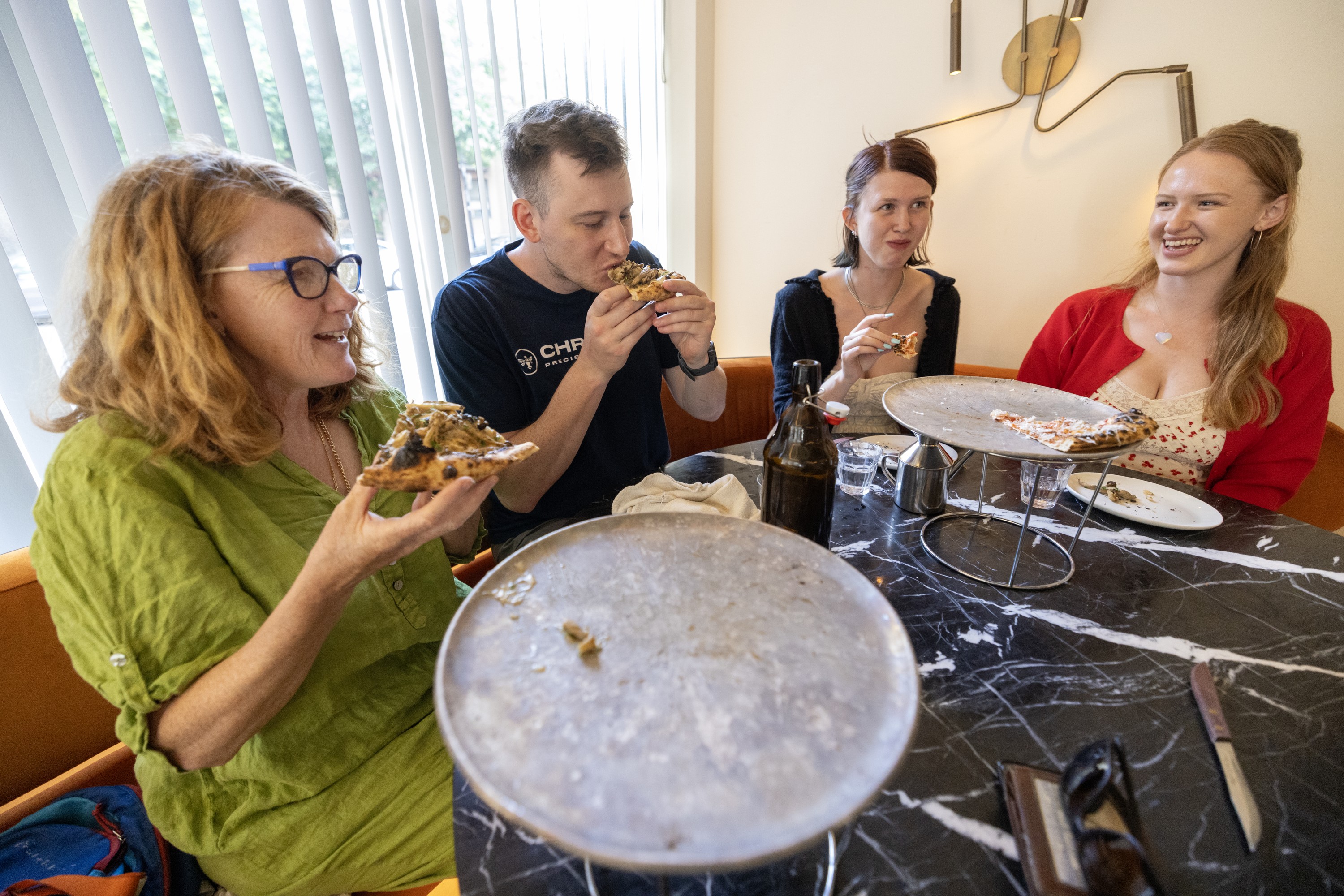 Customers eating two pizza from two platters at Restaurant Elena.