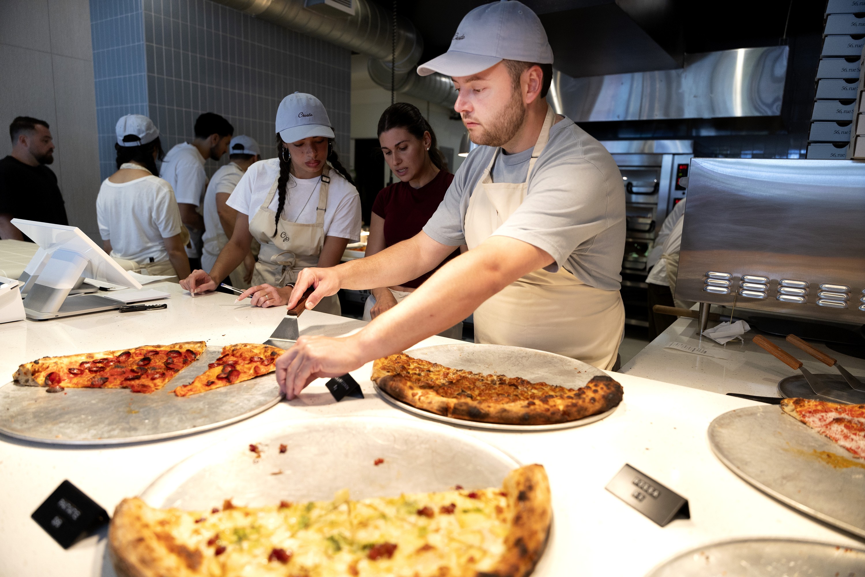 Staff serving up pizza slices at Crosta.
