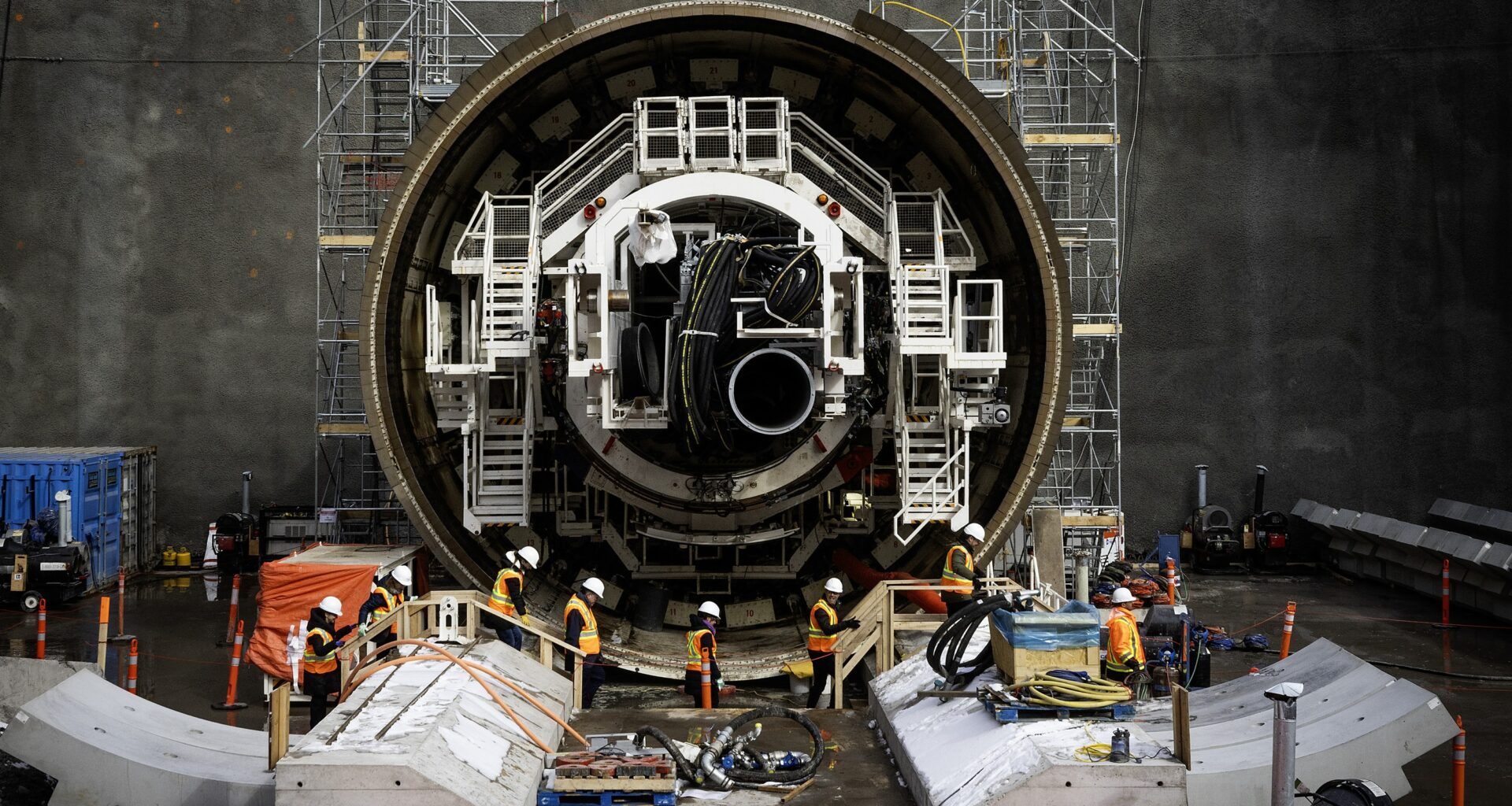 Workers walk in front of a massive tunnel boring machine at the new Vertières métro station on Feb. 23, 2026.