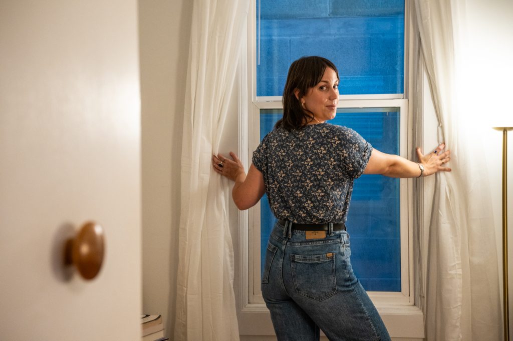 Lucia Whalen looks out of her bedroom window at the cinderblock wall that has been built directly next to her Wicker Park apartment, mon Aug. 17, 2026.