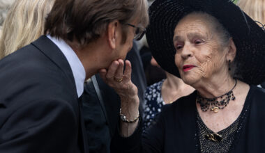 A widow touches the chin of a mourner at a funeral.