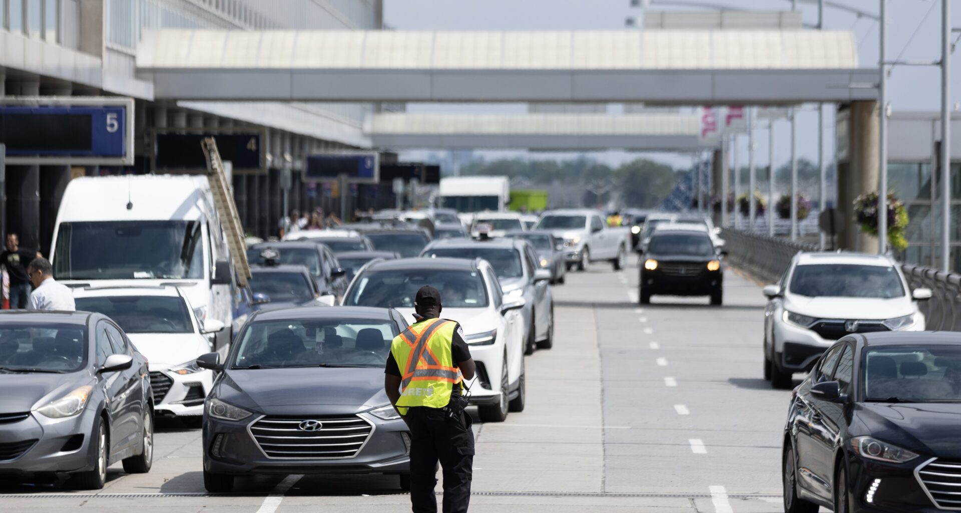A traffic controller directs cars and taxis outside an airport.