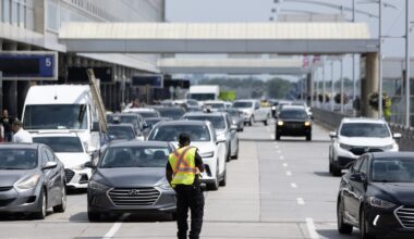 A traffic controller directs cars and taxis outside an airport.