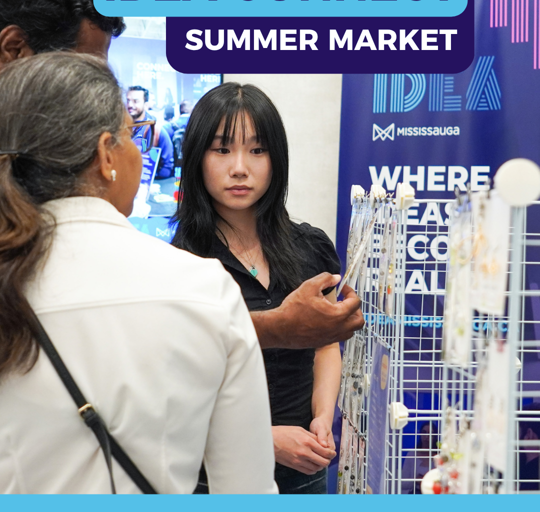 A person shows products to another person with a booth in the background.