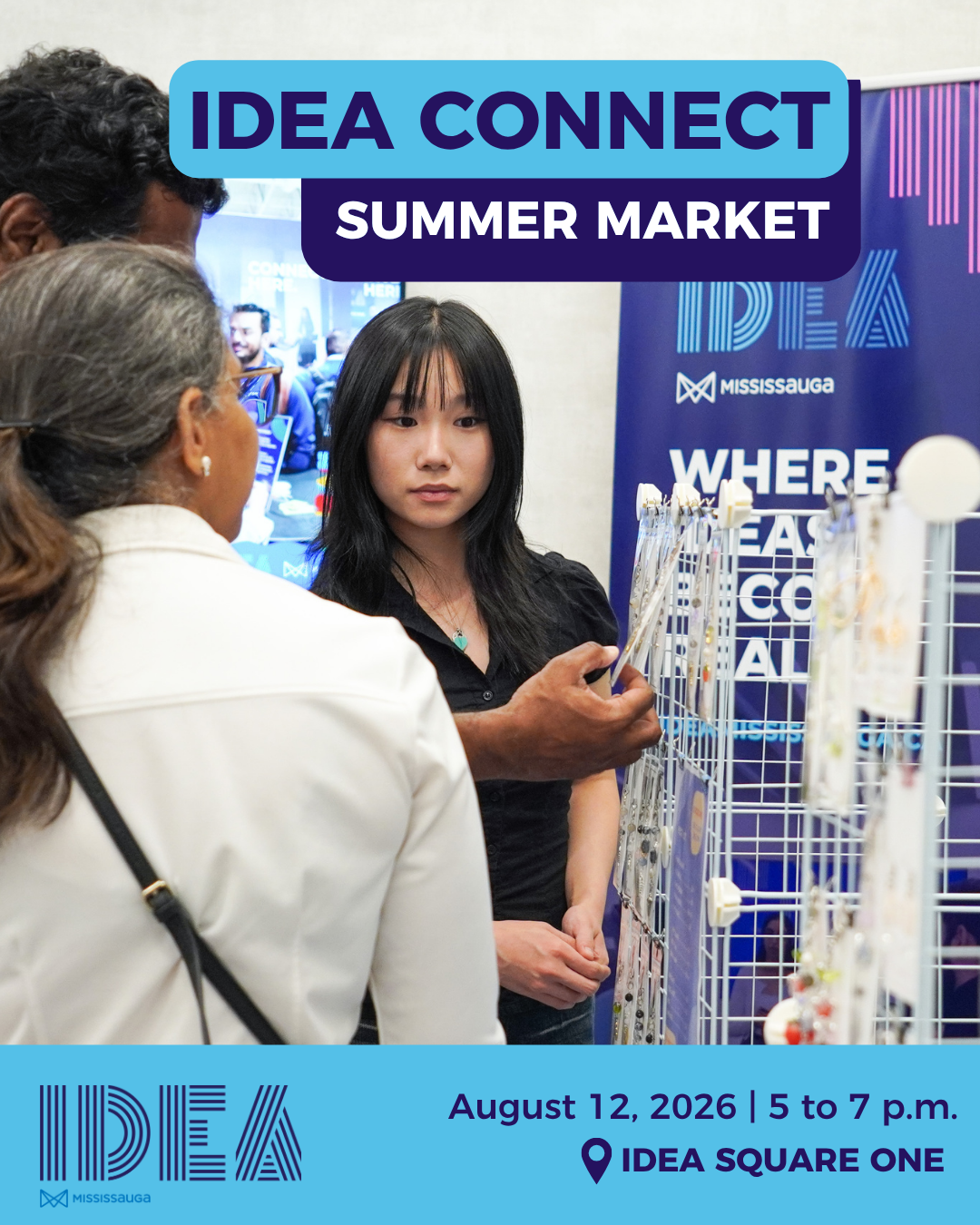 A person shows products to another person with a booth in the background.