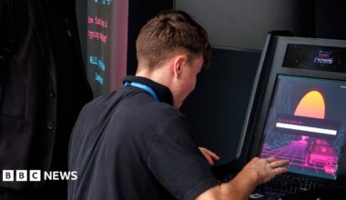 A teenage boy wearing a black polo top plays on an electronic gambling machine with his back to the camera.