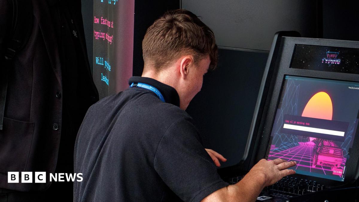 A teenage boy wearing a black polo top plays on an electronic gambling machine with his back to the camera.