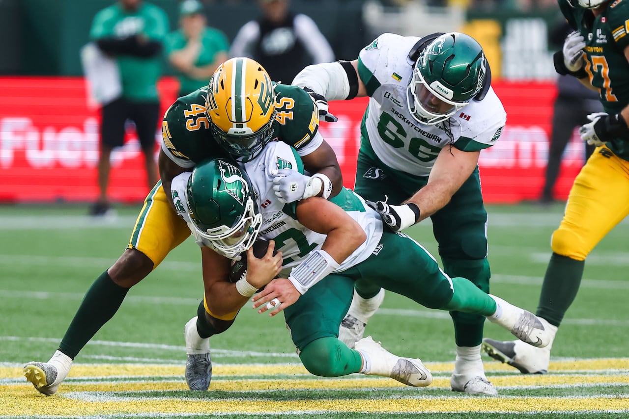 Football player in a green and yellow jersey tackles football player in a green and white jersey.