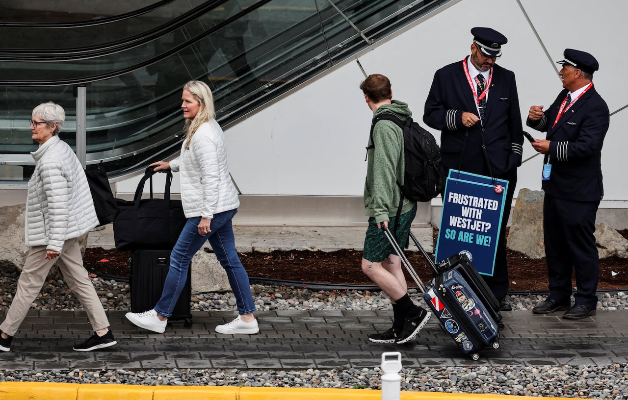 People walk with suitcases tailing behind.