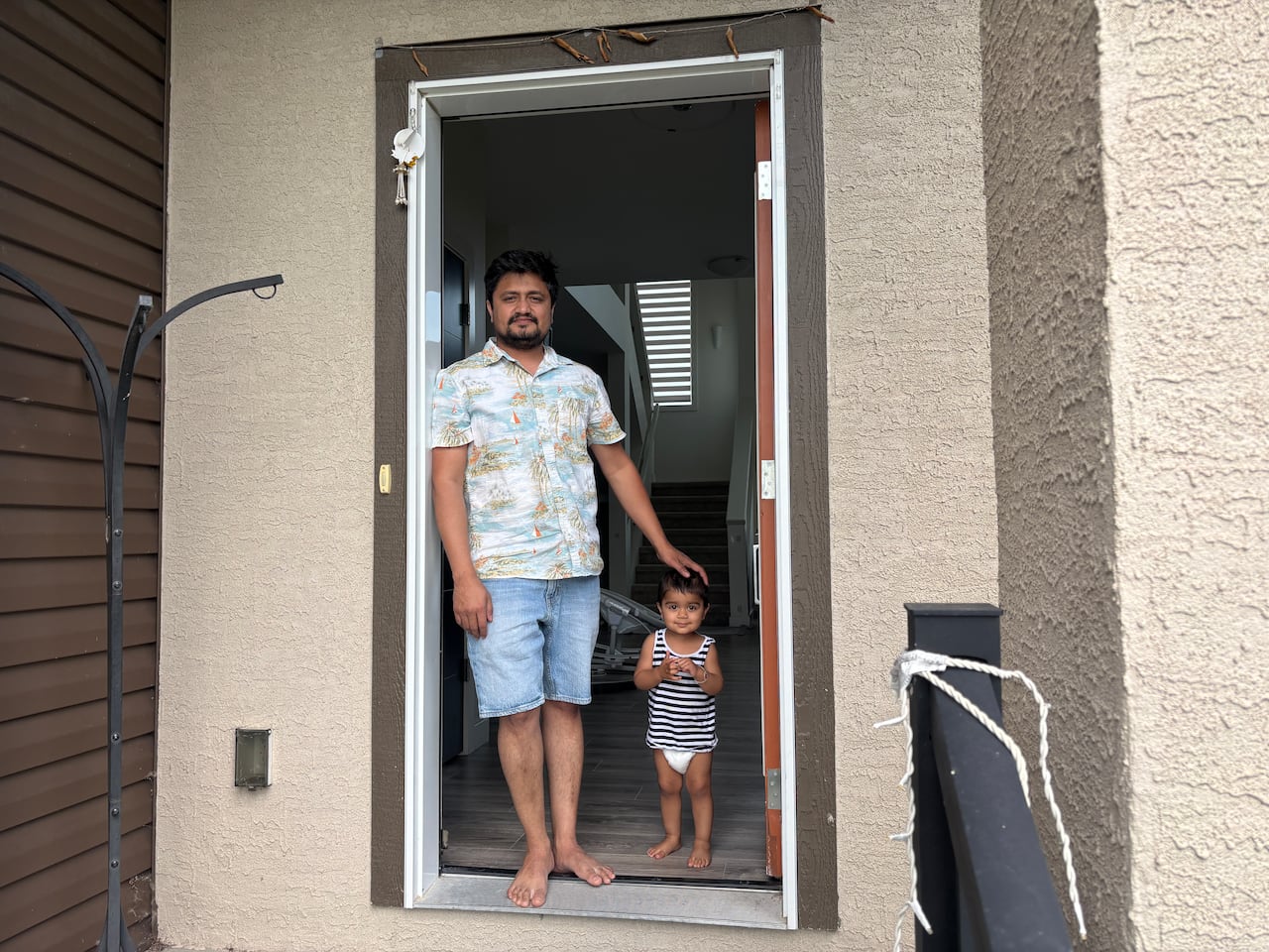A man stands by a doorway with a very young child