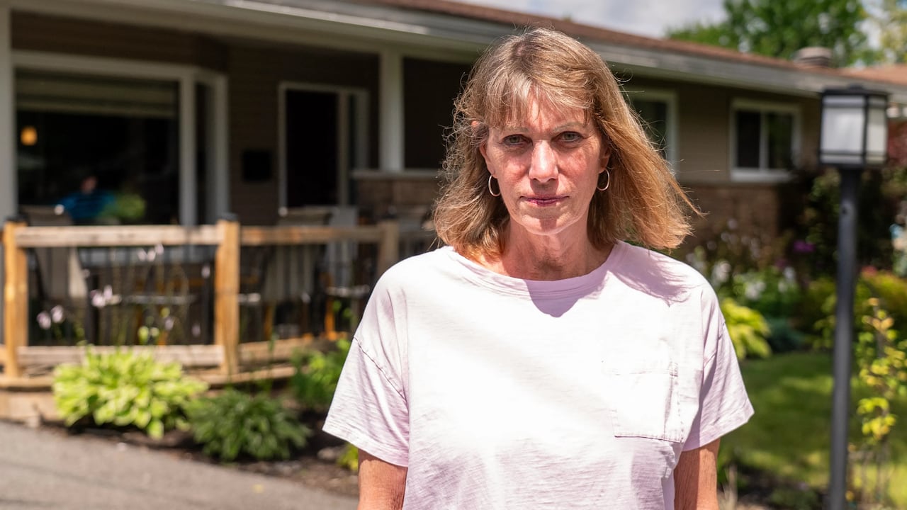 A woman stands in front of a house.