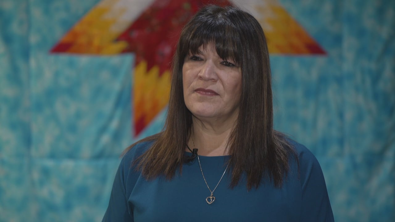 A woman with bangs and a blue top listens during an interview.