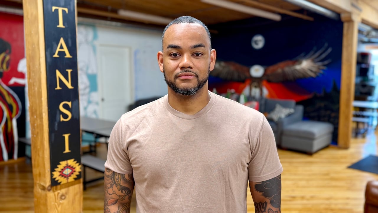 a man in a brown shirt poses in a room