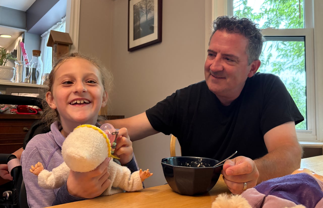 A father looks at his daughter at the breakfast table.