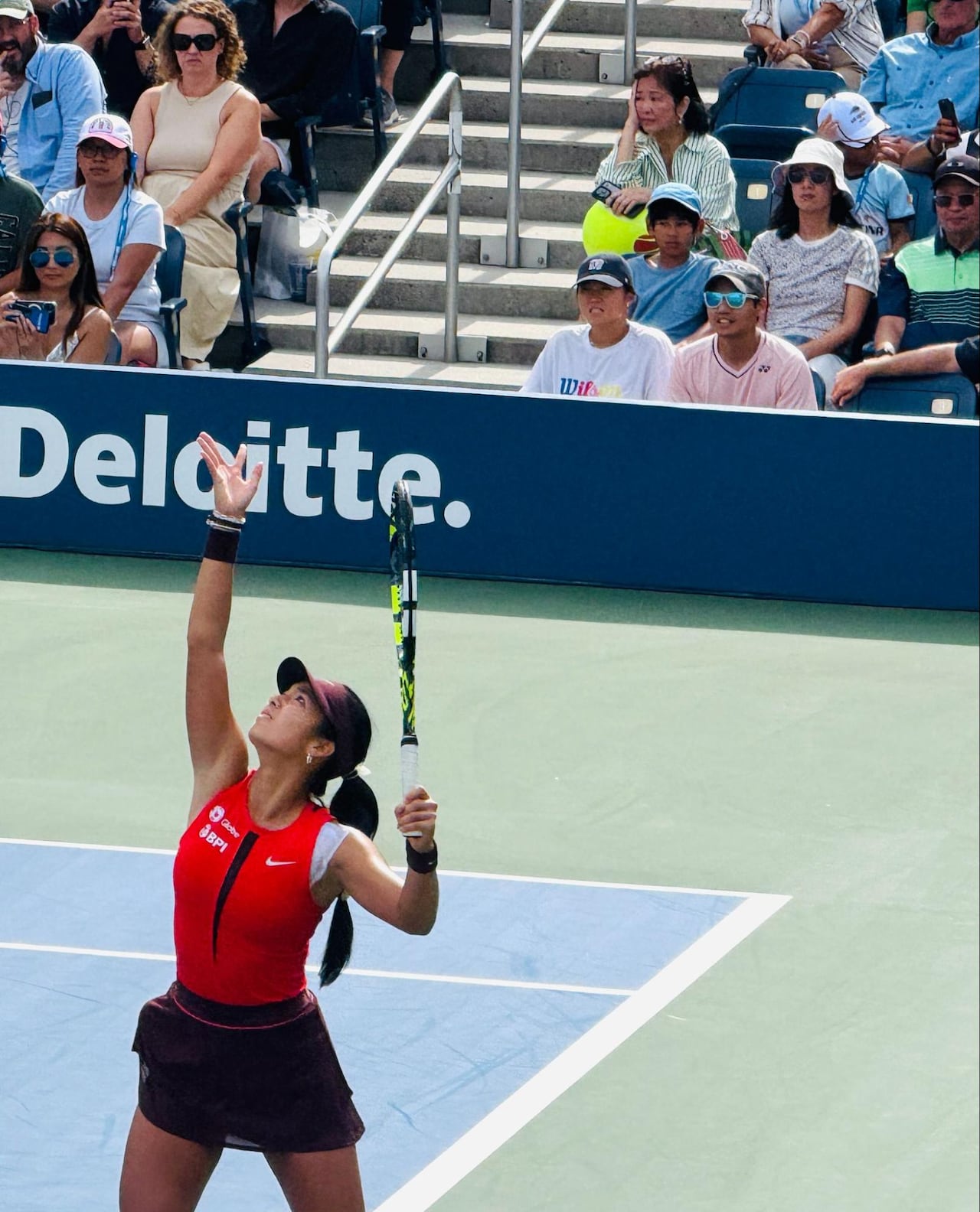 A woman playing tennis is about to serve.