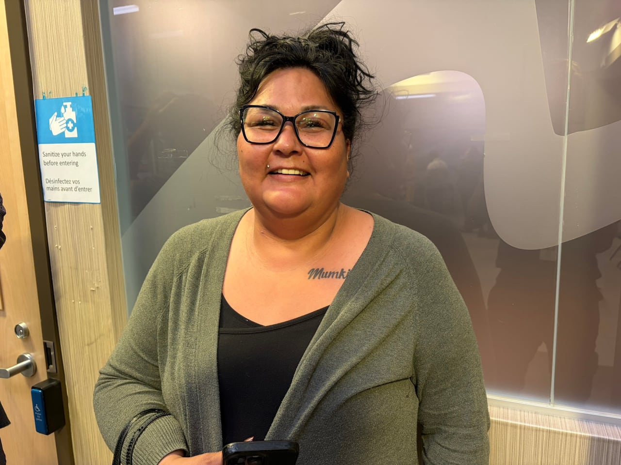 A woman standing in a office building smiles.