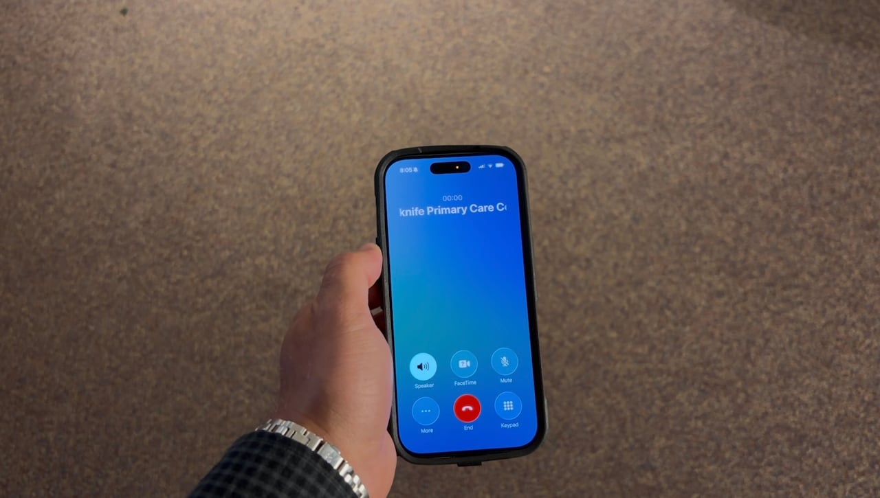 A persons hand holding a phone that is on speaker phone.