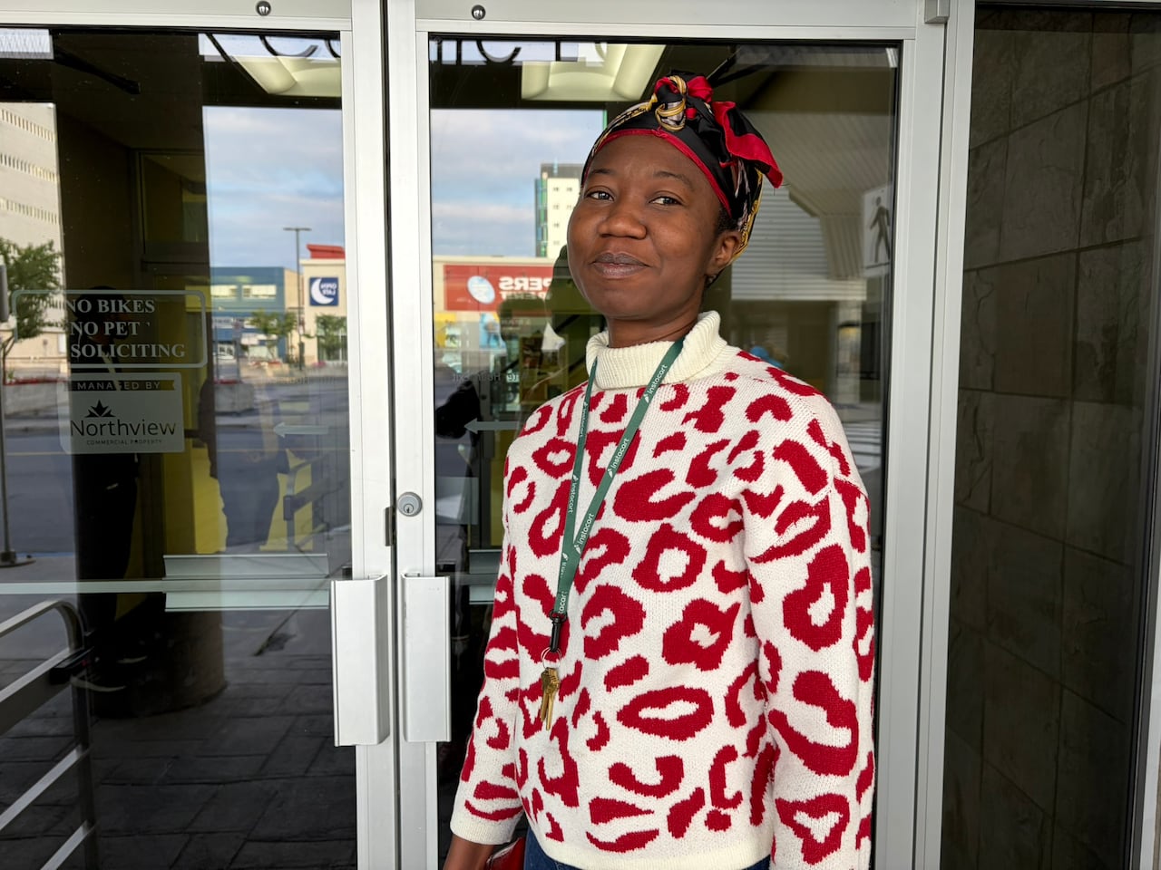 A woman stands outside a glass door.