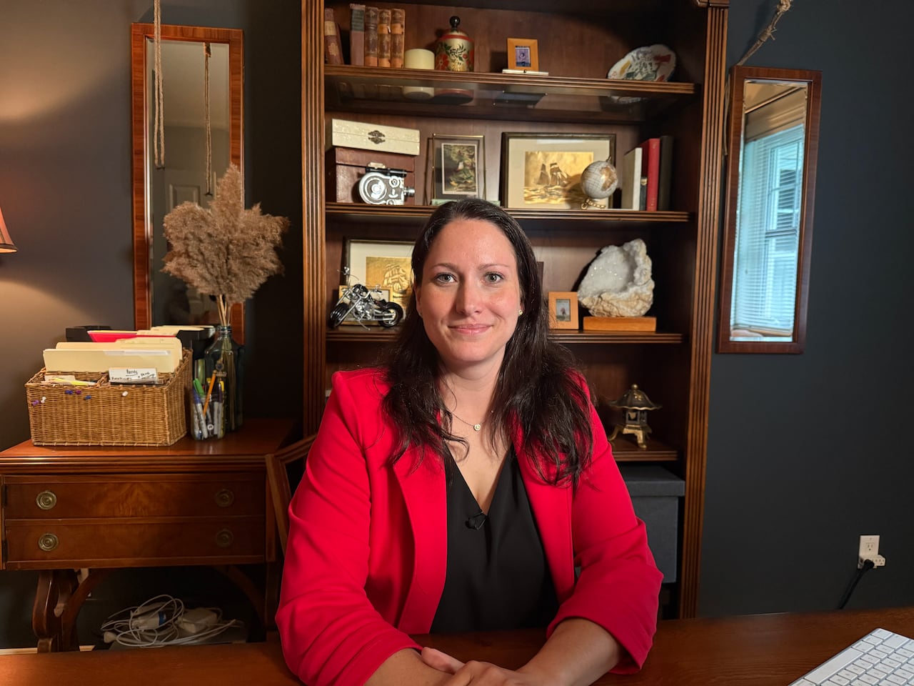women in red blazer is sitting in her office  at a desk