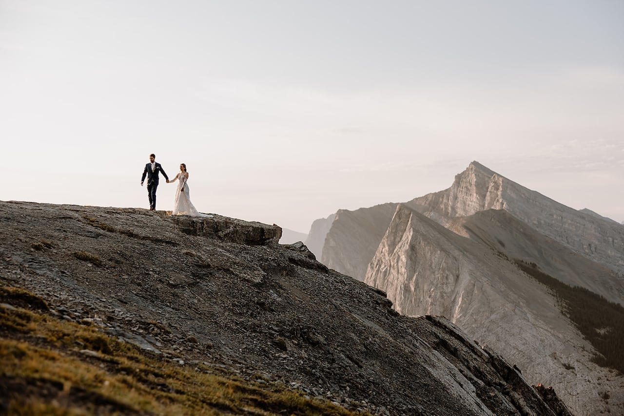 A bride and groom pose for a photo on a glacier.