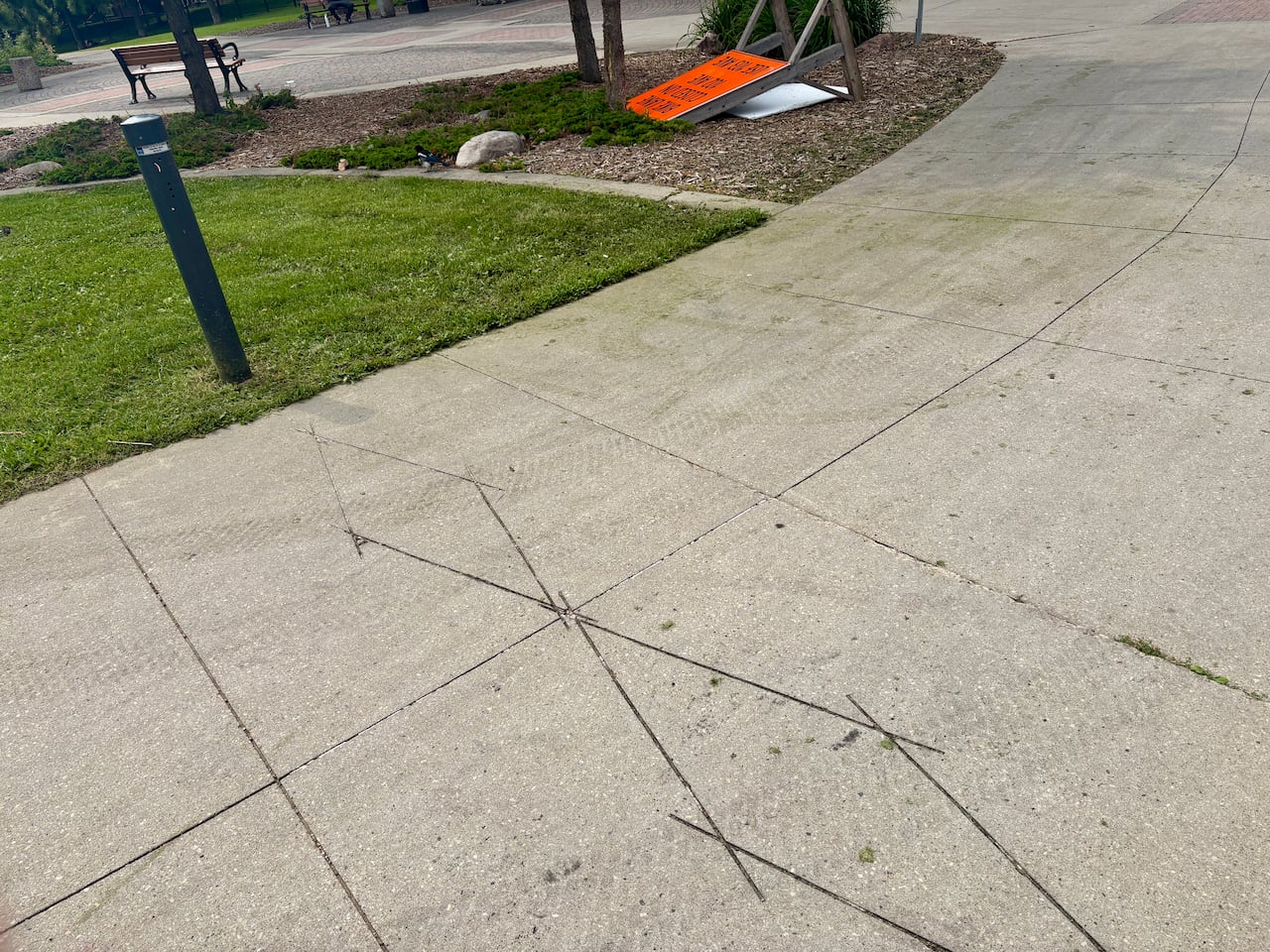 A diamond pattern is seen in the pavement with a post.