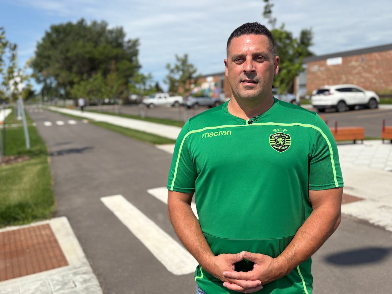 A man in a green jersey stands in front of a bike lane.