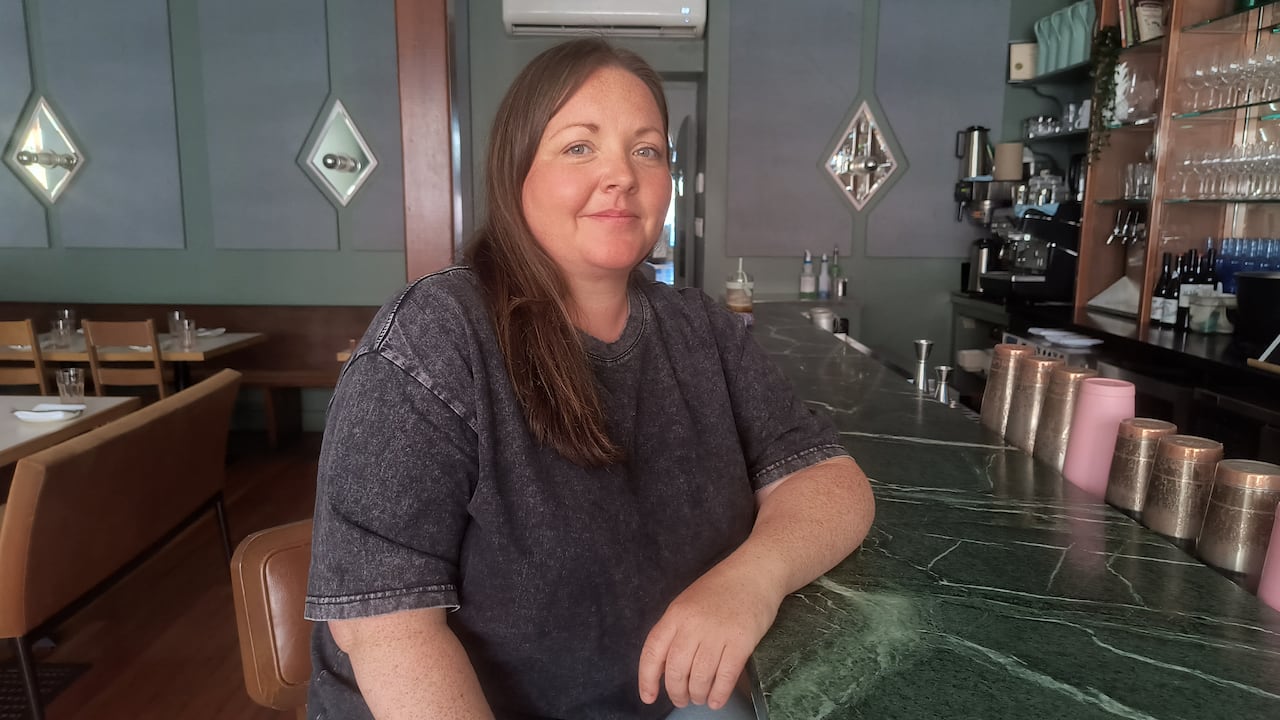 woman sitting at the bar in the front of house of a restaurant