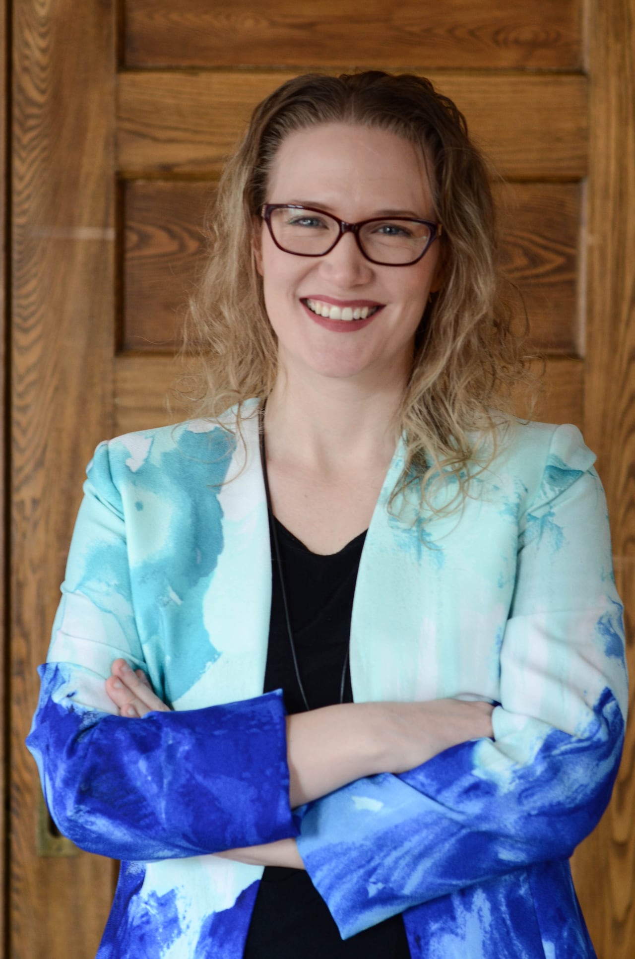 Woman wearing glasses and colourful blazer poses