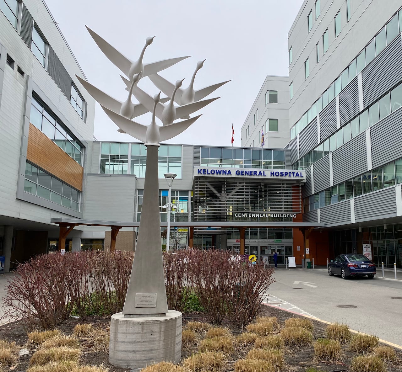 A statue of a number of planes is seen outside a large building with the sign 'Kelowna General Hospital'.