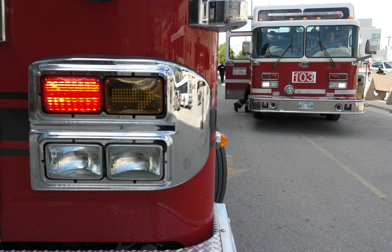 A closeup shows the front of a red fire truck, with another fire truck in the background.